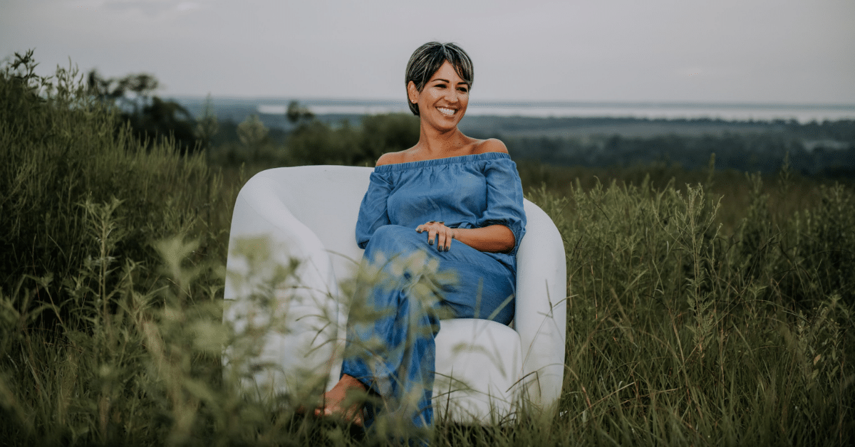 Dr. Alvarez, a women’s cardiologist, sits on a white chair in a field of spring plants